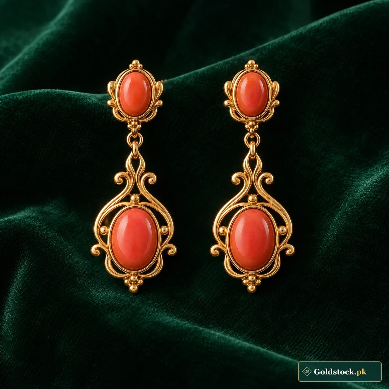 Isha Coral-Accent Earrings: a pair of gold-tone drop earrings with coral-coloured oval accents and small scroll surrounds